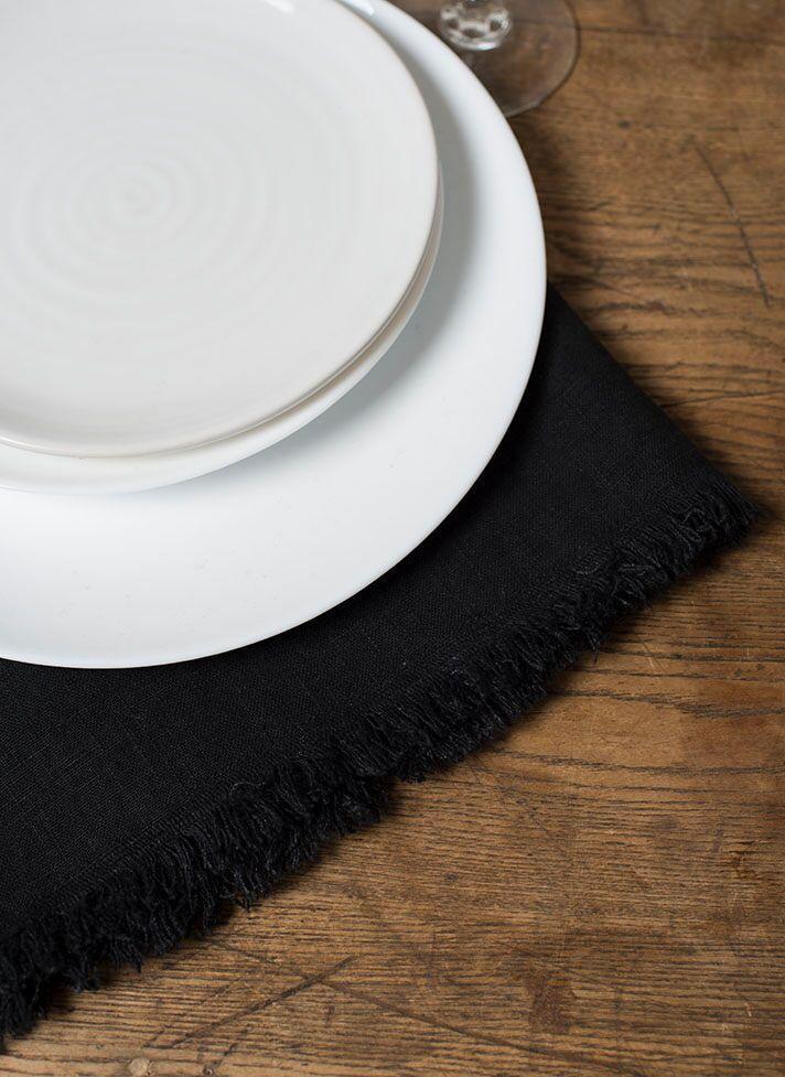 Black linen napkin with fringe on wooden table