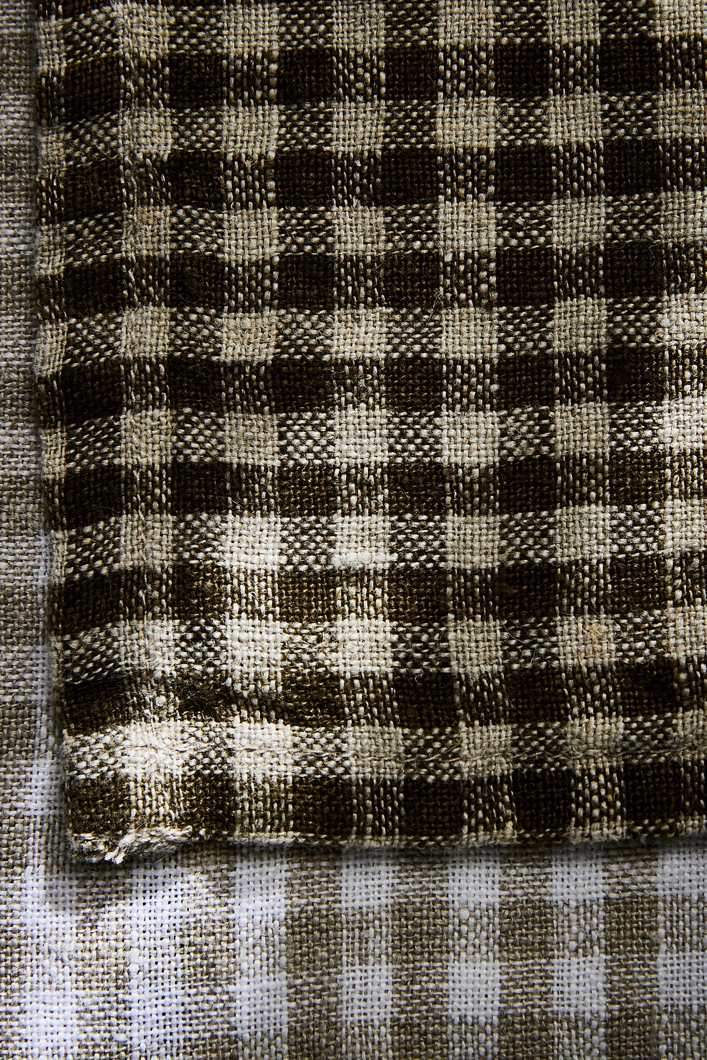 two kitchen towels from La Maison Baude shown overtop of one another in charbon and lin