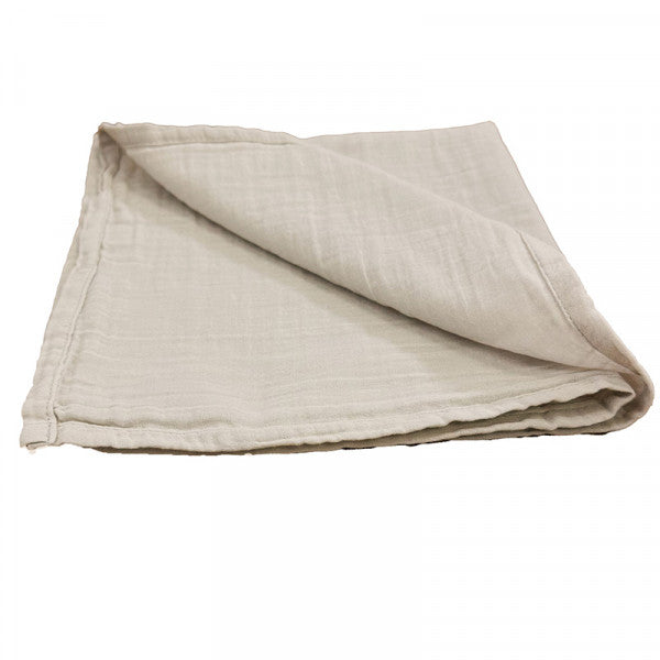 Cotton gauze tablecloth in natural folded up against white background