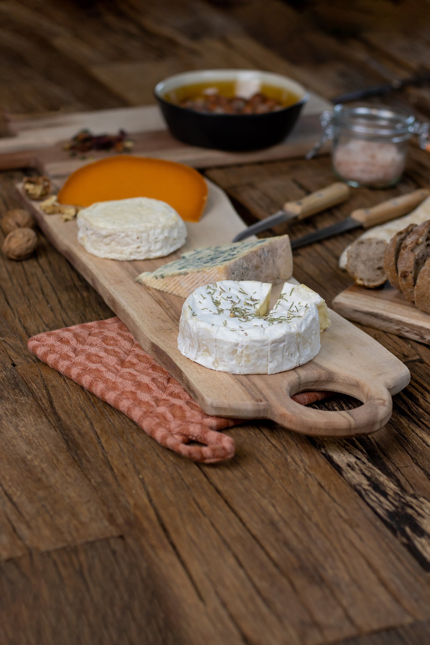 Acacia wood cheese board with four kinds of cheese on wooden table