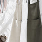 Three cross-back linen aprons hanging from a clothing line