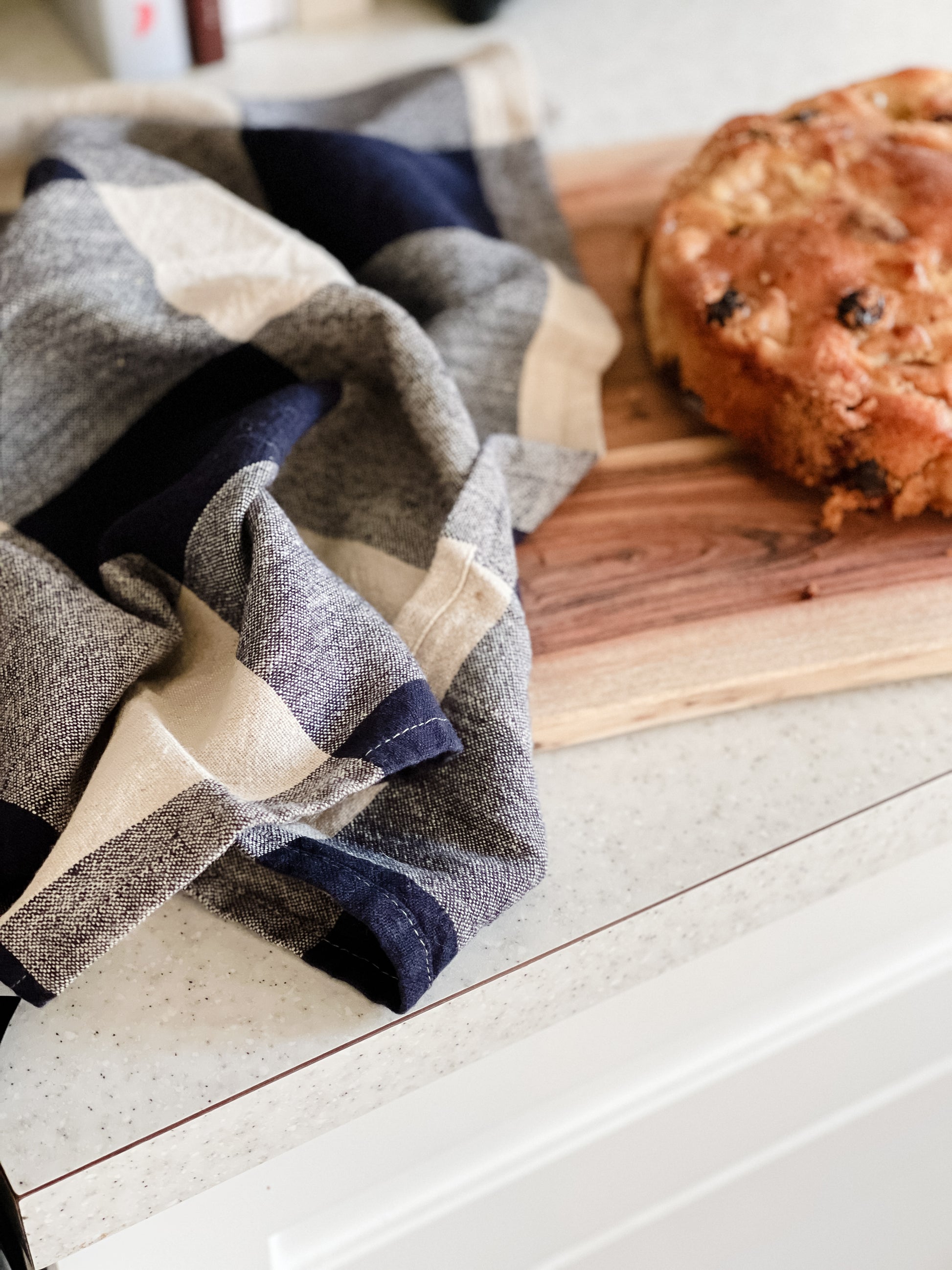 Navy Checkered Linen Kitchen Towel on countertop beside raisin cake