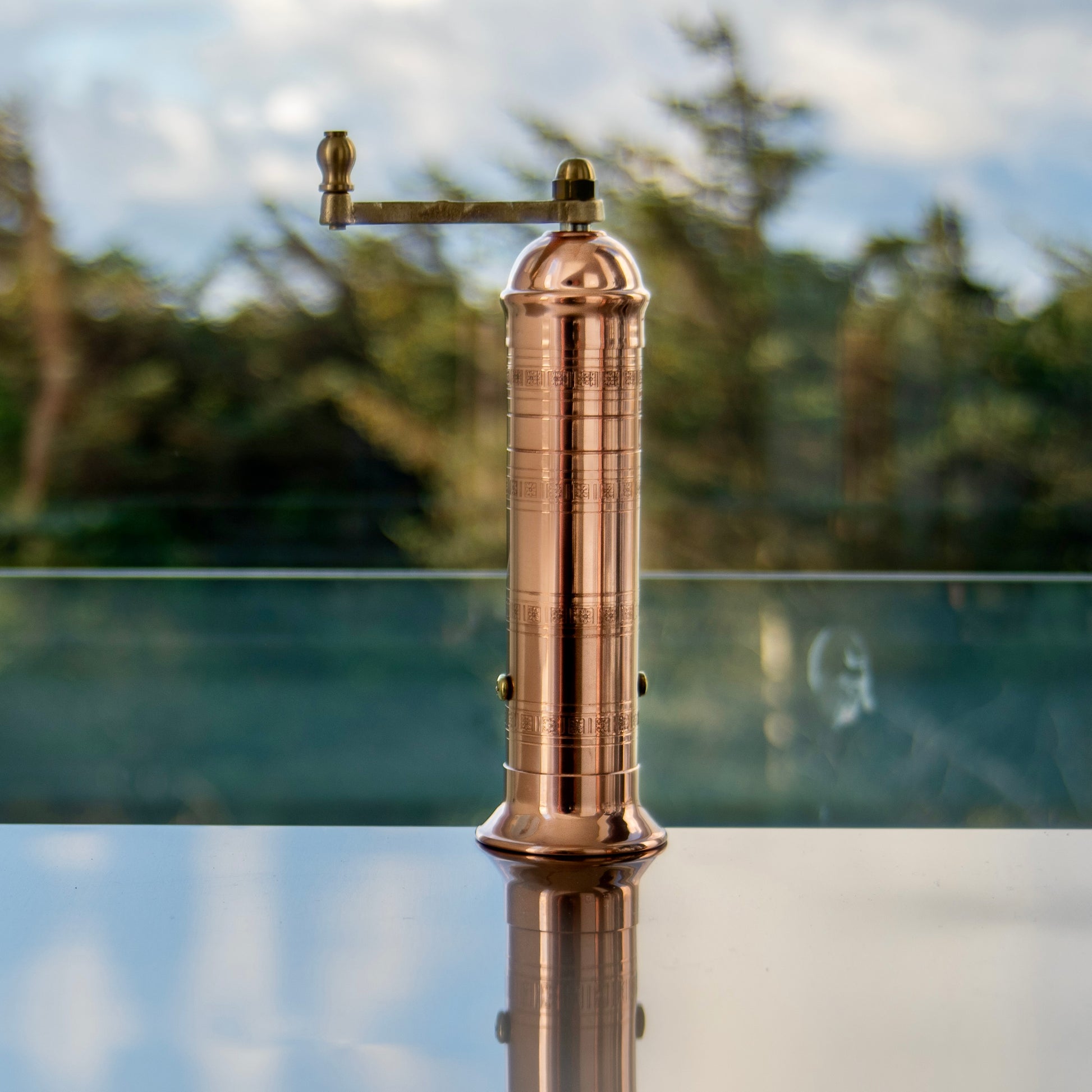 Copper pepper grinder against mirrored background